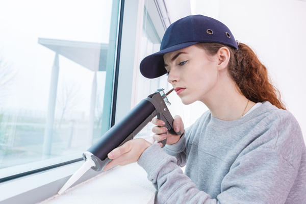 image of woman sealing window to prevent air leaks