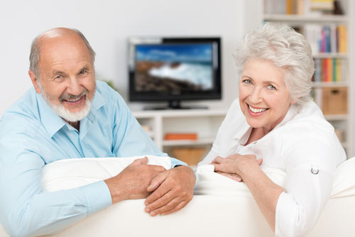older couple watching tv in AC cooled house
