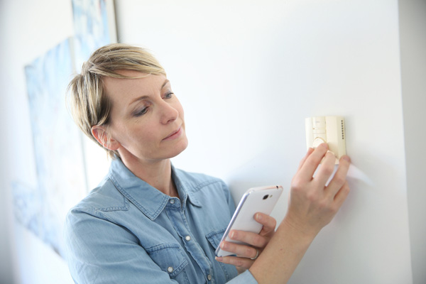 image of a homeowner adjusting a programmable thermostat
