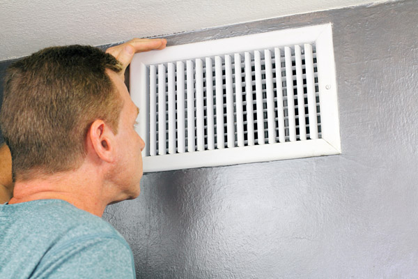 image of homeowner placing hands in front of vent due to hvac airflow issues