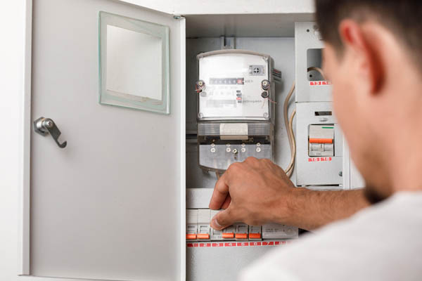 image of a homeowner at electrical panal checking air conditioner circuit