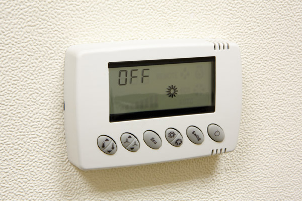 image of hand adjusting thermostat due to air conditioner outside unit not working