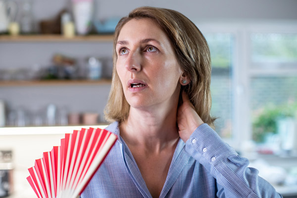 image of a homeowner using a fan to keep cool due to hvac unit not cooling due to closed hvac vents