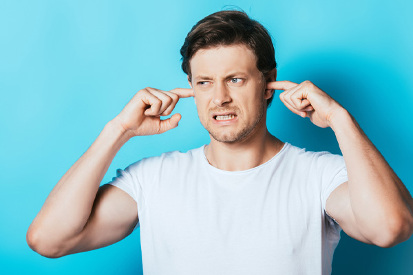 image of a homeowner covering ears due to window AC unit making noise