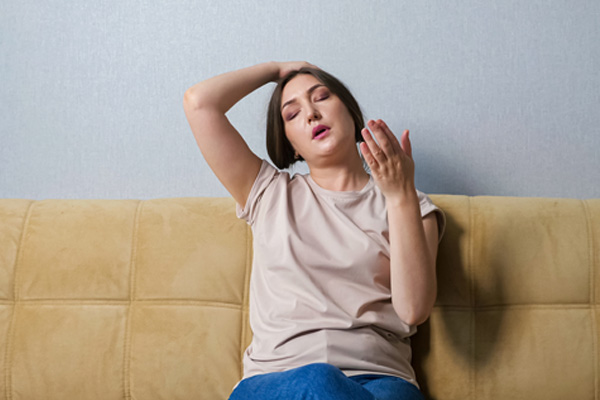 woman suffering from heat at home depicting air balancing and hvac system