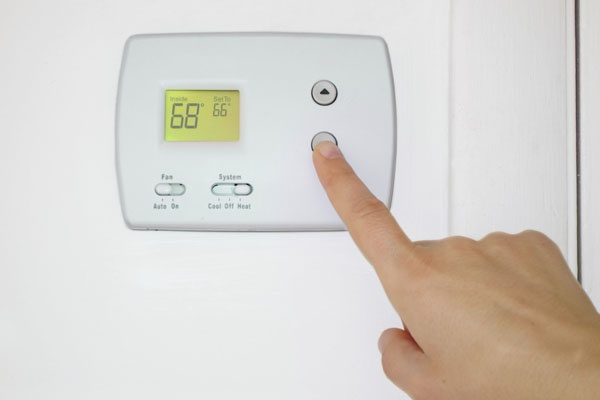 image of homeowner adjusting thermostat