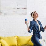 Woman holding bottle of aerosol air freshener at home