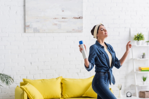 Woman holding bottle of aerosol air freshener at home that can impact IAQ