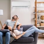 couple lounging in the living room couch controlling ductless mini-split