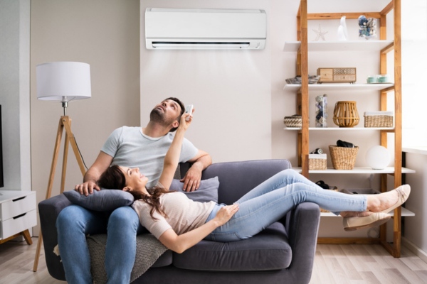 couple lounging in the living room couch controlling ductless mini-split