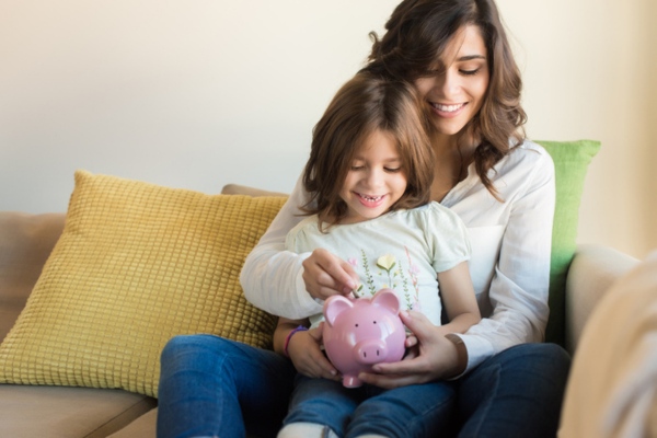 mother and daughter putting some money in piggy bank depicting energy bill savings