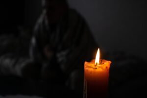 candle and man in a warm blanket in the background depicting generator won't start